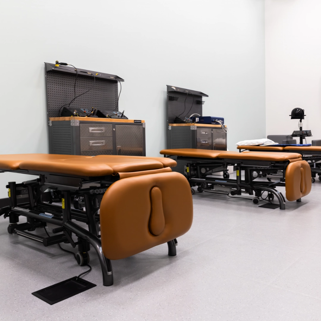Modern treatment room with chiropractic tables and rehabilitation equipment.